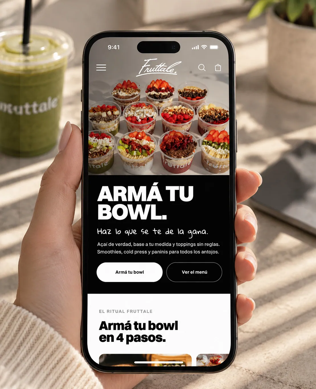 Fruttale online store open on a phone held next to a smoothie